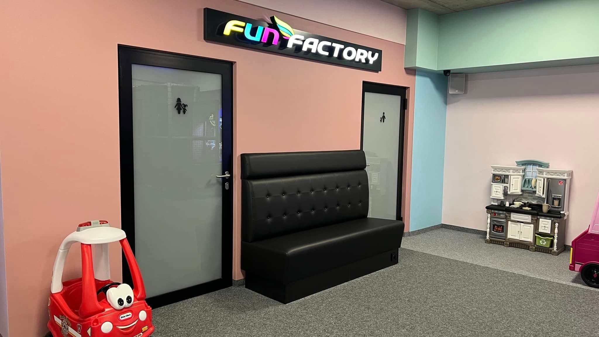 Wejście do Fun Factory z neonem, kącikiem zabaw i toaletą rodzinną