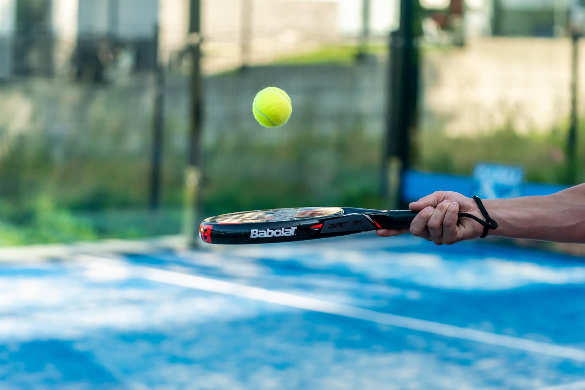 Rakieta Babolat i piłka nad niebieską nawierzchnią kortu