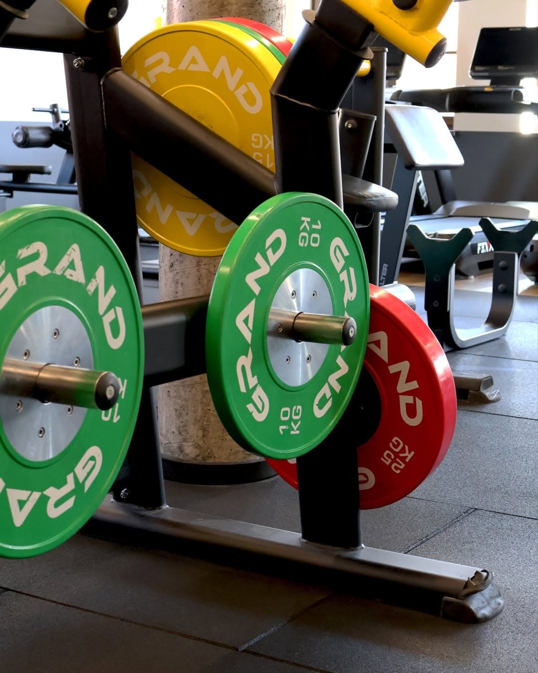 Kolorowe talerze olimpijskie na stojaku przy strefie cardio